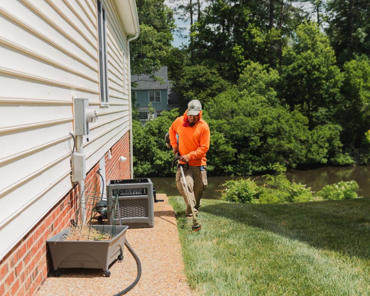 A crew member pressure washing a walkway alongside the house